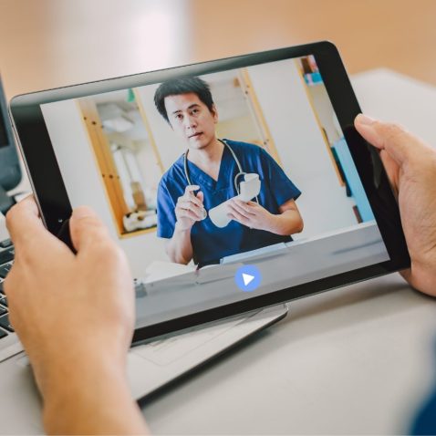 a pair of hands holding a digital screen and watching a video