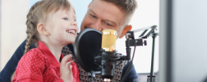 A child and adult standing infront of professional studio microphone