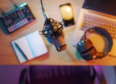 Professional audio equipment, notebook, laptop and smartphone on the desk in the home studio, microphone in the foreground, top view: content creation, livestreaming and entertainment concept