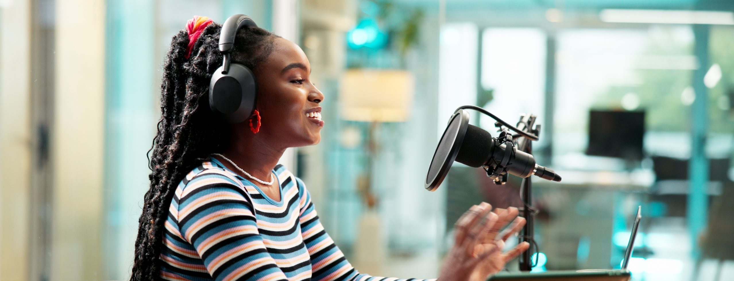 Talking, headphones and black woman on podcast with microphone for broadcast or radio host. Laptop, happy person and live streaming in studio for show, production or content creation for social media