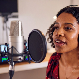 dark skinned woman recording infront of a studio microphone