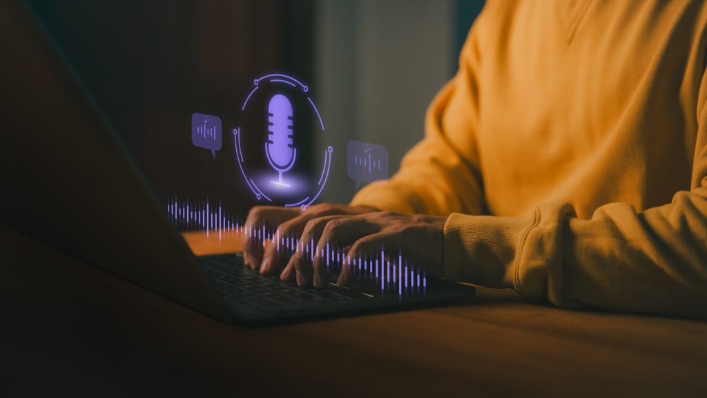 Person typing on laptop computer with glowing voice assistant icon, representing AI voice recognition, speech-to-text, and virtual assistant technology for modern communication and productivity.